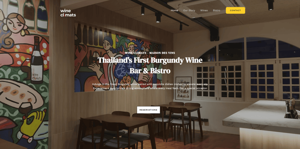 พื้นหลังเว็บไซต์ภายในร้าน Wine Climats Maison des Vins ตกแต่งสไตล์โมเดิร์นอบอุ่น มีงานศิลปะสีสันสดใสบนผนัง โต๊ะอาหารไม้โทนวอร์ม บรรยากาศส่วนตัวเหมาะสำหรับดื่มไวน์เบอร์กันดี